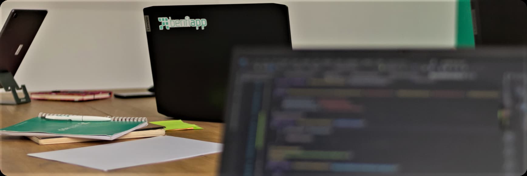 Laptops on a desk with Beriflapp Logo sticker on the back and coding screen blurred